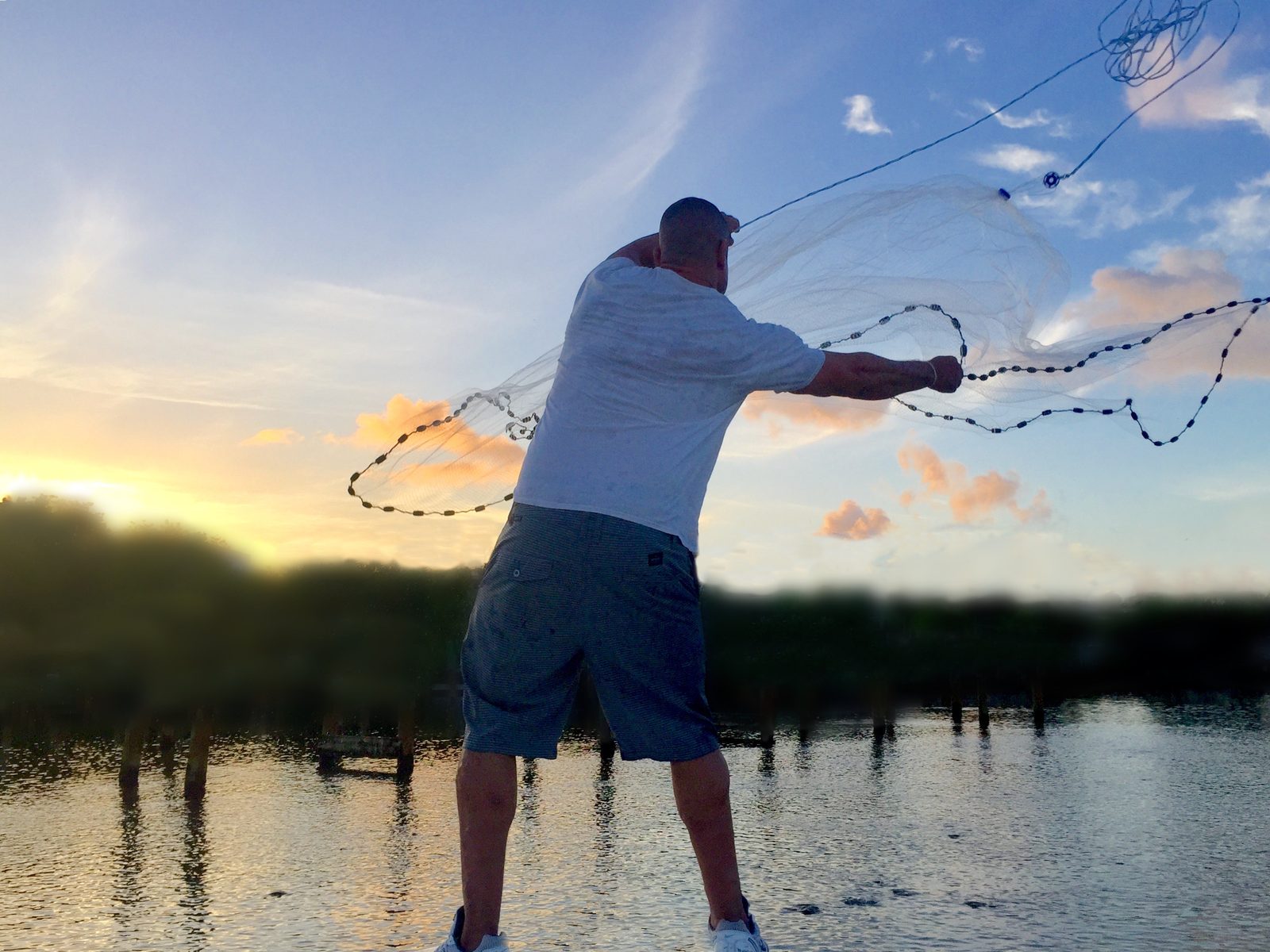 Jeff Howell throwing a cast net for bait at sunset